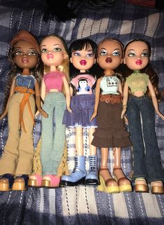 five dolls are lined up on a bed