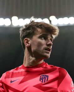 a close up of a soccer player wearing a red uniform and looking off to the side