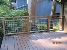 a wooden deck with metal railing next to trees