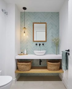 a bathroom with two baskets under the sink and a mirror on the wall above it