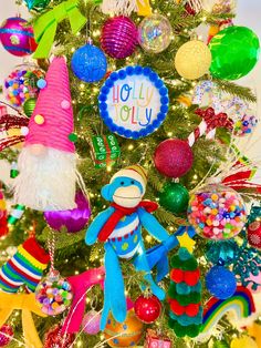 a christmas tree decorated with brightly colored ornaments and an ornament that says holly jolly