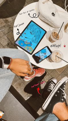 a person sitting at a table with their feet on the table and two cell phones in front of them