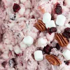 a bowl filled with marshmallows, cranberry salad and pecans