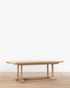 a wooden table sitting on top of a hard wood floor next to a white wall