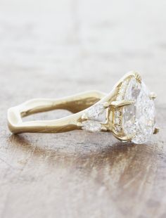 an old - fashioned diamond engagement ring sits on a wooden surface