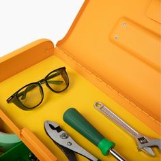 an open tool box with various tools in it, including eyeglasses and pliers