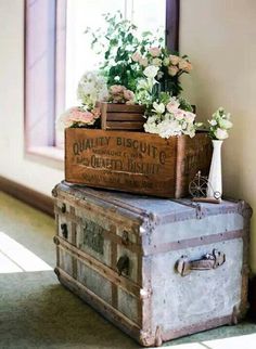 an old trunk with flowers in it sitting next to a window