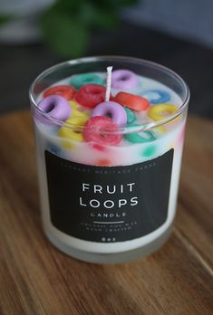 a candle with fruit loops in it sitting on a wooden table next to a plant