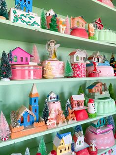 shelves filled with brightly colored christmas decorations and houses on top of each shelf, all decorated in pastel colors