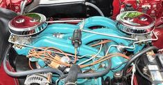 the engine compartment of an old car with red and blue paint on it's hood