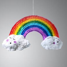 a rainbow made out of tissue paper hanging from a string with two pom poms