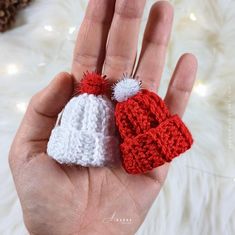 a hand holding two crocheted hats in it's palm, one is red and the other is white