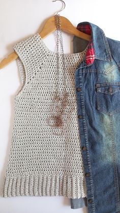 two pieces of clothing hanging on a wooden hanger next to a denim jacket and sweater