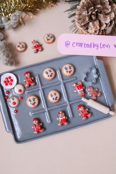 a cookie tray with decorated cookies on it next to pine cones and other holiday decorations