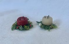 two small candles sitting on top of a white cloth covered table next to each other