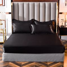 a bed with black sheets and pillows in a room