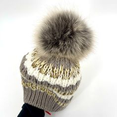 a knitted hat with a pom - pom attached to the front and side