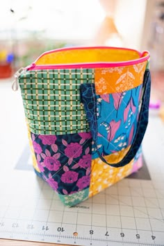 a multicolored bag sitting on top of a cutting board next to a ruler