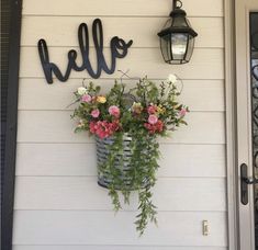 a basket with flowers hanging from the side of a house next to a light fixture