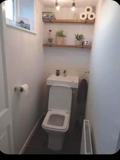 a small bathroom with a toilet, sink and shelf above the toilet is shown in this image