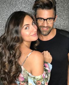 a man standing next to a woman in front of a glitter wall with her arm around him