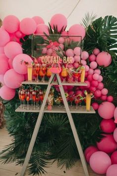 a cocktail bar with pink balloons and palm leaves