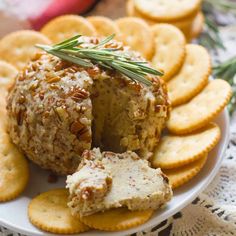 crackers and cheese ball on a plate with rosemary sprig