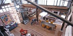 an aerial view of a living room and dining area in a loft with exposed ceilings