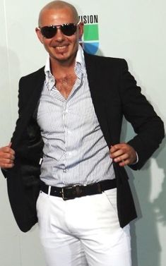 a bald man with sunglasses on posing for the camera while wearing white pants and a black blazer