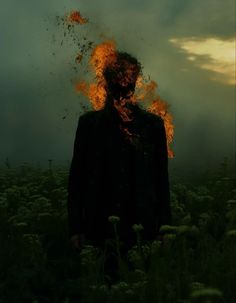 a man standing in the middle of a field with fire coming out of his face