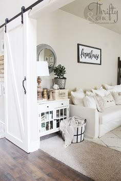 a living room with white couches and wooden floors in front of a barn door