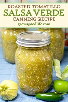 two jars filled with salsa and green peppers on top of a blue towel next to garlic