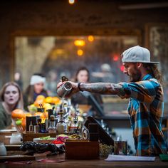 a man pouring something into a glass at a bar