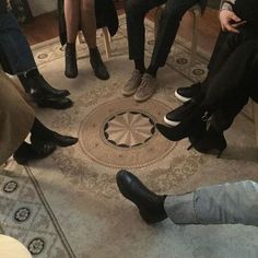 four people are sitting in a circle on the floor with their feet propped against each other