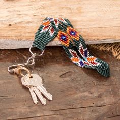 a key chain with two keys attached to it on top of a piece of wood