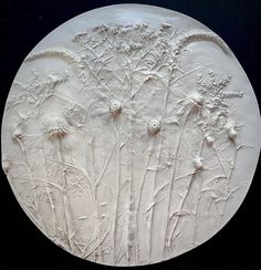 a white plate with flowers on it sitting in front of a black background and the bottom part of the plate is made out of clay