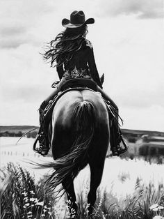 a black and white photo of a woman riding a horse in a field with tall grass