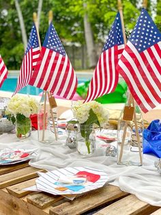 an outdoor table with american flags on it and place settings in front of the pool