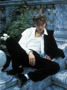 a young man sitting on top of a stone bench