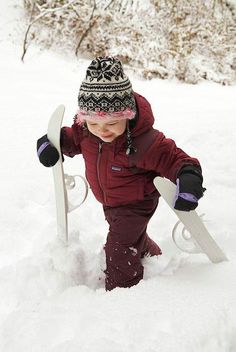 a small child in the snow with skis