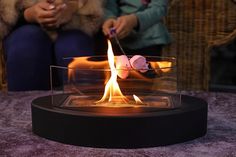 a woman sitting on a chair next to a fire pit with marshmallows in it