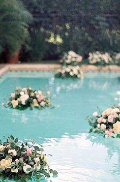 flowers are arranged on the edge of a swimming pool for an outdoor wedding ceremony or reception