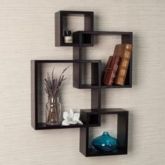 two black shelves with books and vases on each shelf in front of a wall