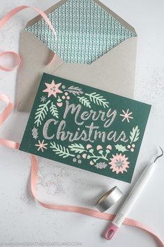 a christmas card with pink and green flowers on it next to a crafting kit