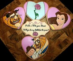 decorated cookies with disney characters on them sitting on a wooden table in the shape of hearts