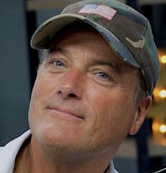 a close up of a person wearing a hat and looking off to the side with an american flag on his cap