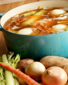 a bowl of soup with carrots, potatoes and celery on a table