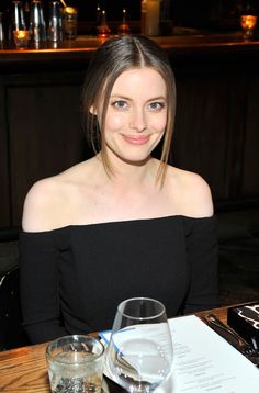 a beautiful young woman sitting at a table with a glass of water in front of her