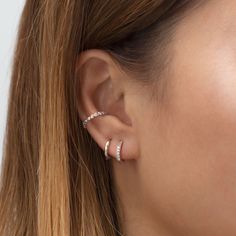 a close up of a woman's ear with two diamond hoops on it