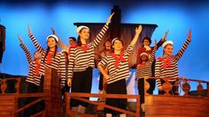 a group of people standing on top of a wooden stage with their arms in the air